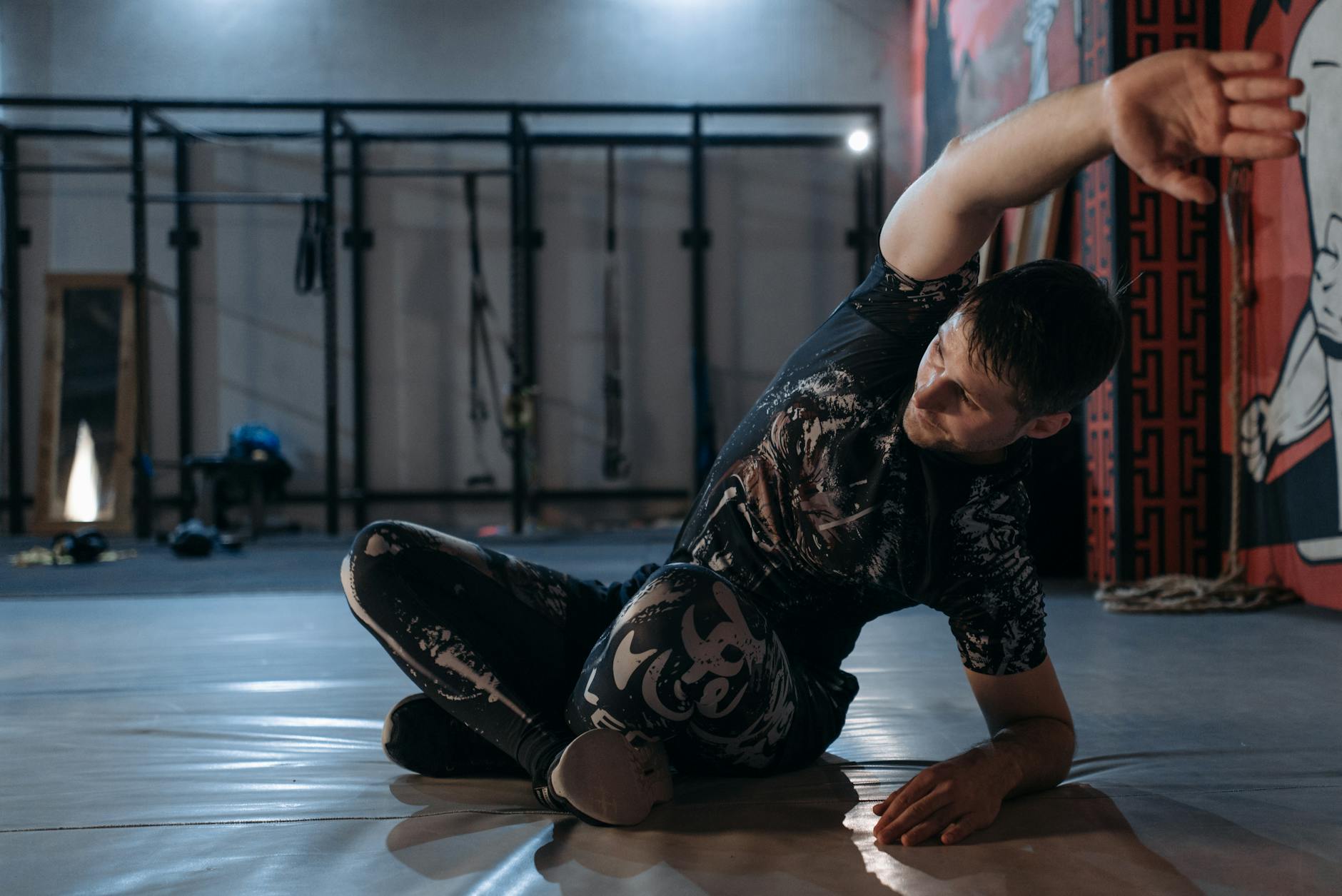 Mężczyzna rozciąga się na macie w sali treningowej przed siłownią