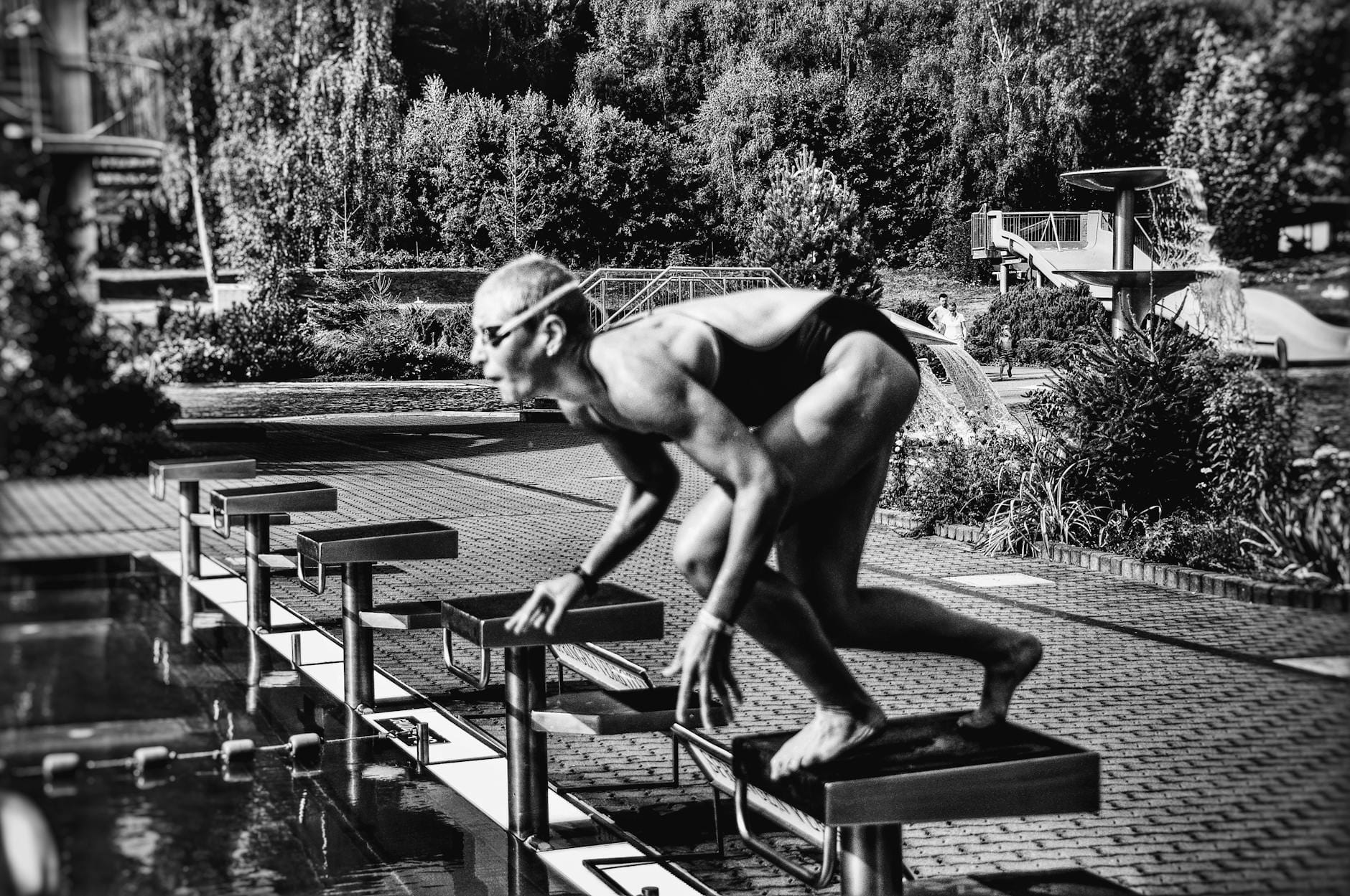 Pływaczka w stroju startowym pochylona na słupku przy basenie