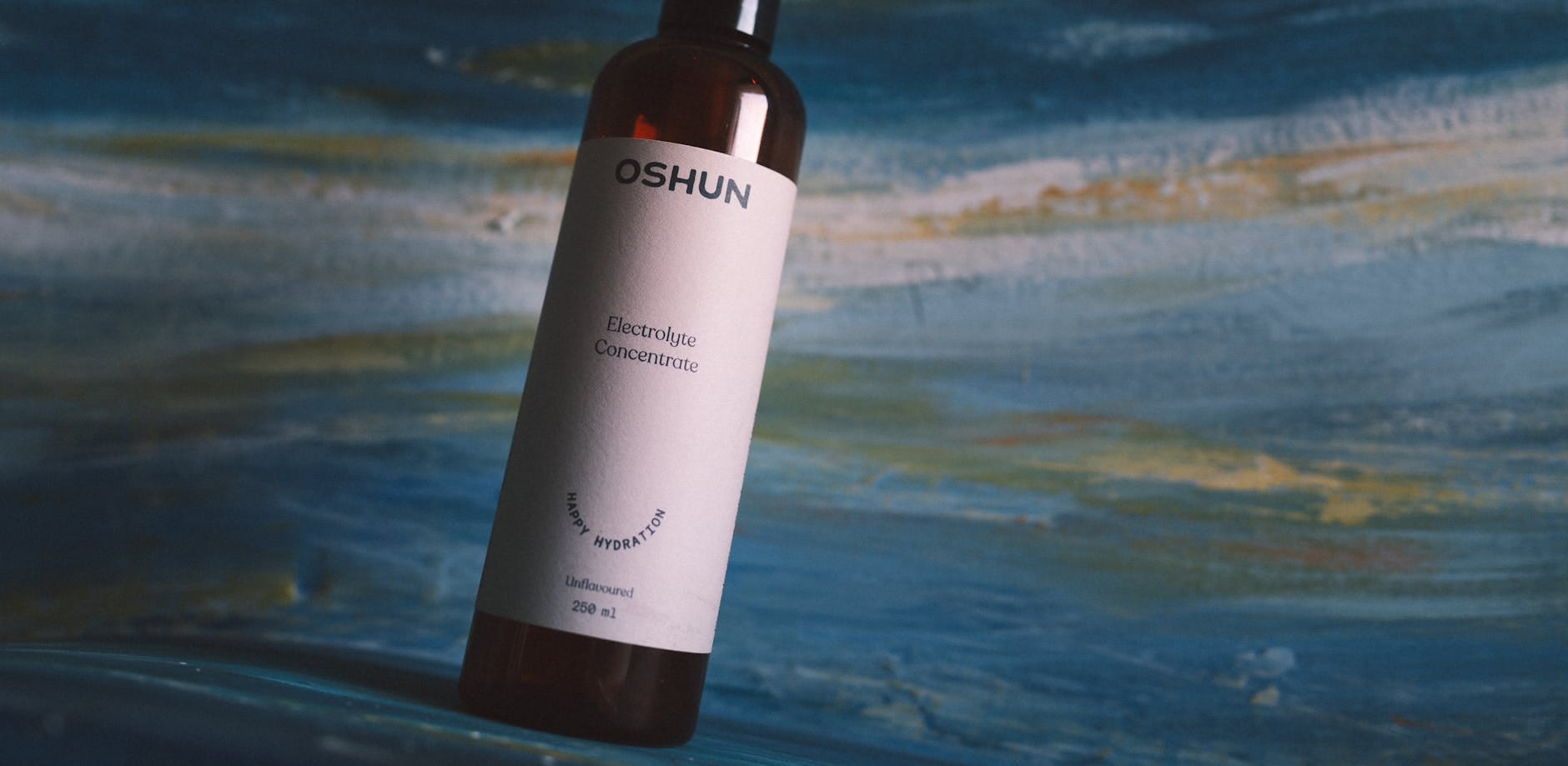 Zbliżenie butelki koncentratu elektrolitów Oshun na fakturowanym tle