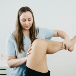 Co zabrać na sesję wibroterapii i jak się ubrać, żeby było wygodnie Fizjoterapeuta prowadzi terapię nogi pacjenta w gabinecie rehabilitacji