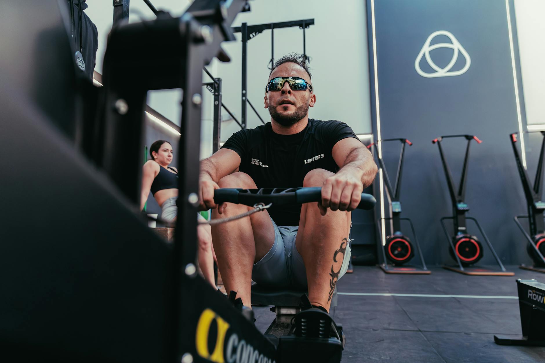 Mężczyzna skupiony na wiosłowaniu na maszynie w nowoczesnej siłowni