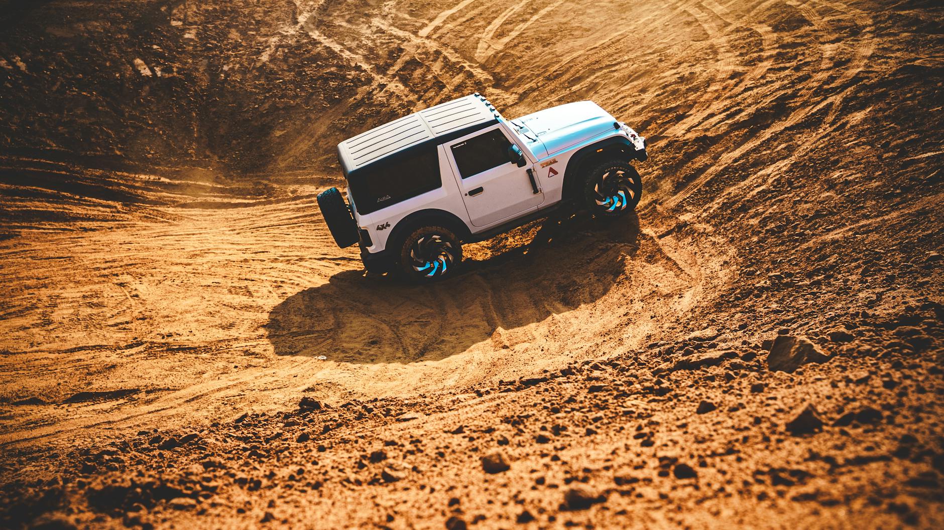 SUV jadący dynamicznie po piaszczystych wydmach podczas off-roadu