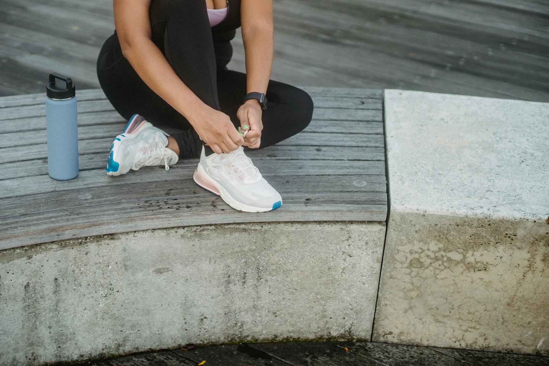 Kobieta wiąże buty sportowe na ławce przed treningiem