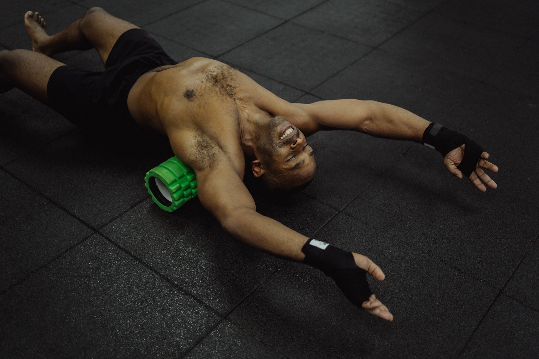 Mężczyzna w klubie fitness roluje mięśnie nóg na wałku