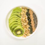 Dieta a zakwasy: co jeść, by szybciej wracać do treningu Miska smoothie z jogurtem, kiwi, orzechami i nasionami jako zdrowe śniadanie