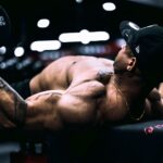 Najlepsze ćwiczenia na plecy na siłowni bez bólu lędźwi Skupiony sportowiec ćwiczy z hantlami na siłowni, wzmacniając mięśnie pleców