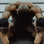 Stretching po treningu: jak rozciągać, żeby nie tracić stabilizacji Mężczyzna na podłodze siłowni wykonuje ćwiczenia rozciągające po treningu