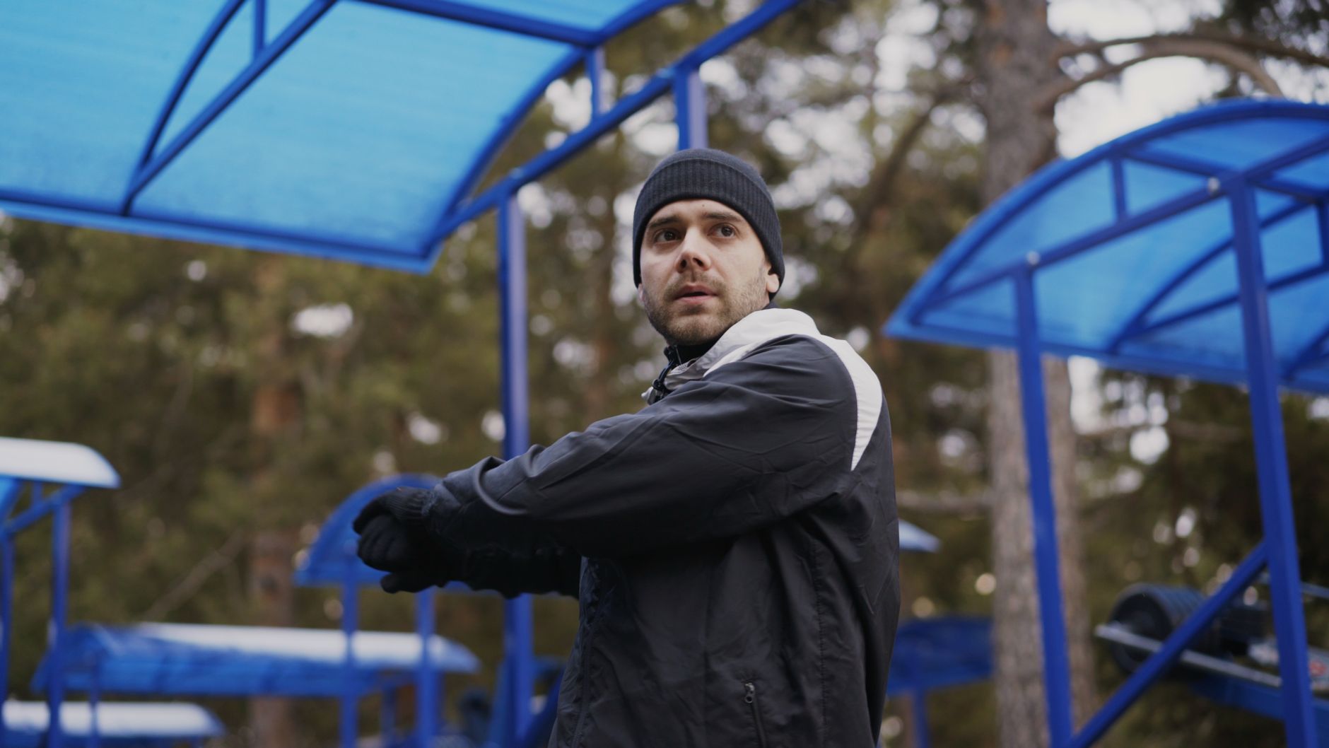 Mężczyzna w zimowym stroju sportowym ćwiczy w parku pod zadaszeniem